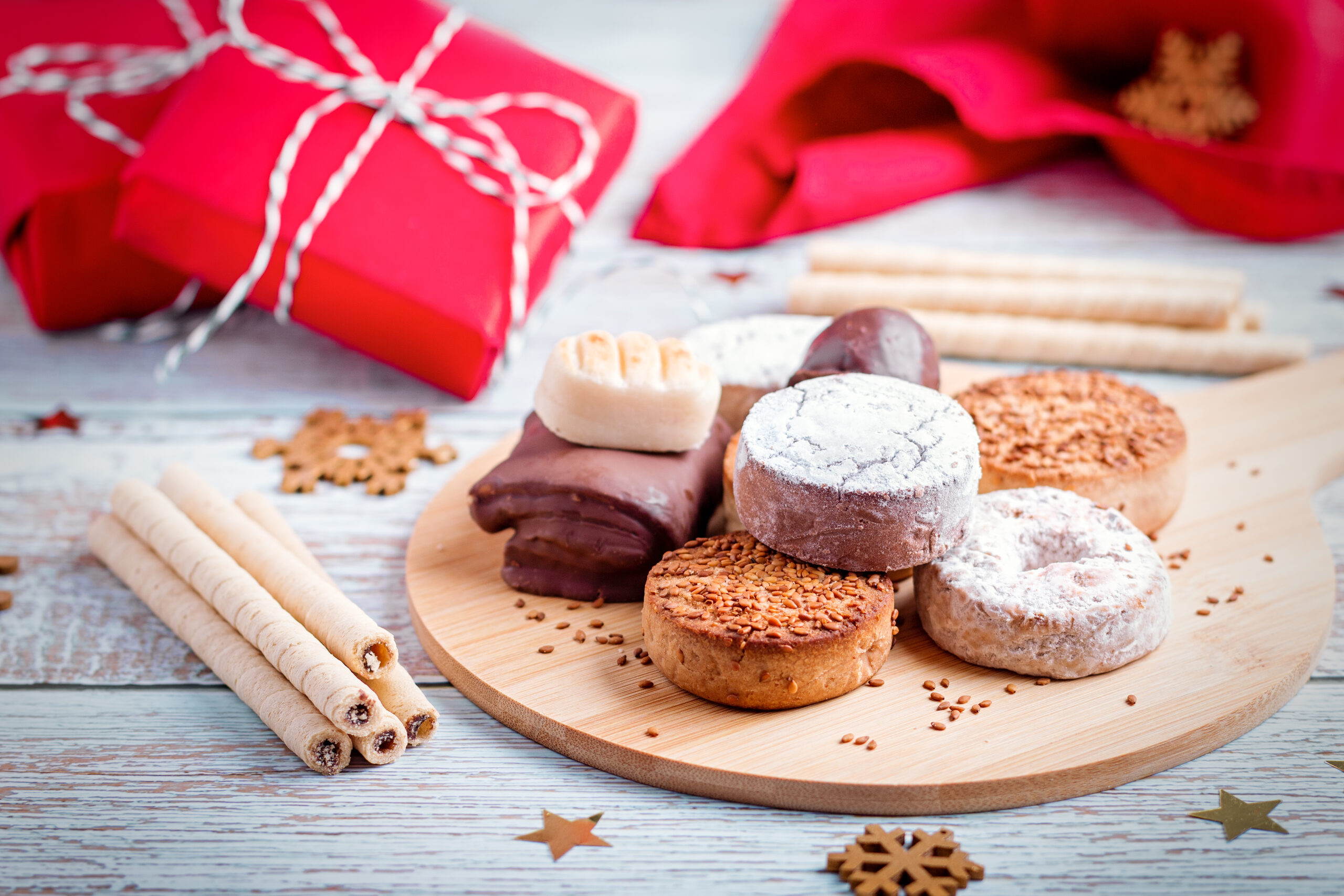 Traditional Spanish Christmas sweets turron, polvorones, mantecados with Christmas decor and red gift boxes on light wooden table top, copy space Traditional Spanish Christmas sweets turron, polvorones, mantecados on grey table top